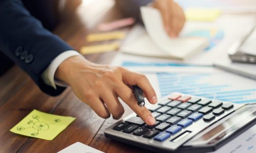 Businessman using calculator to calculate budget and analyzing sales data and growth graph, Payments, Business financing and accounting banking.